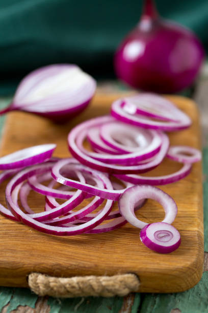 красный лук на разделоной доске - spanish onion стоковые фото и изображения