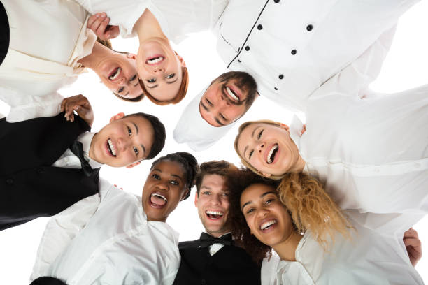 Smiling Restaurant Staff Standing Against White Background Low Angle View Of Happy Restaurant Staff Standing Against White Background food and drink establishment stock pictures, royalty-free photos & images
