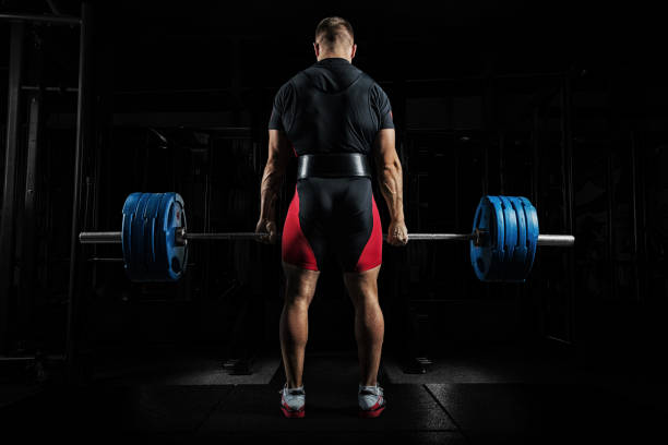 istock Professional athlete is standing and is holding a very heavy barbell. 909303770