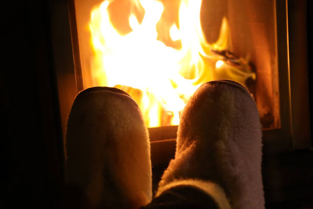 istock Feet in wool socks warming at the fireplace 909306958