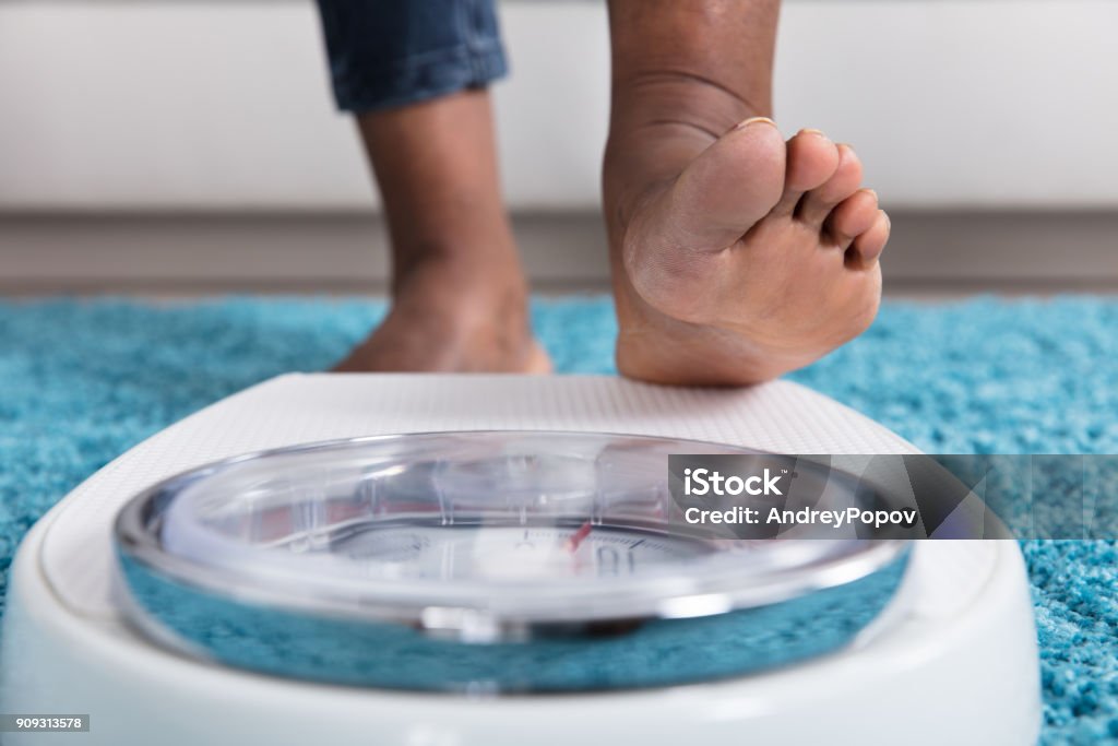 Human Foot Stepping On Weighing Scale Close-up Of A Human Foot Stepping On Weighing Scale Scale Stock Photo