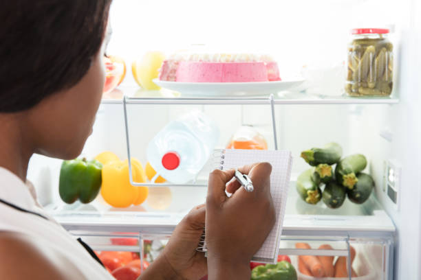 istock Woman Writing On Spiral Book Near Refrigerator 909314124