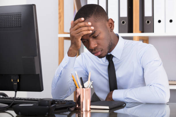 istock Businessman Sitting With Head In Hand At Desk 909314692