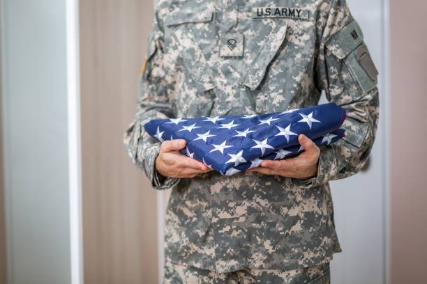 istock Soldier Presenting USA Flag Folded 909316870