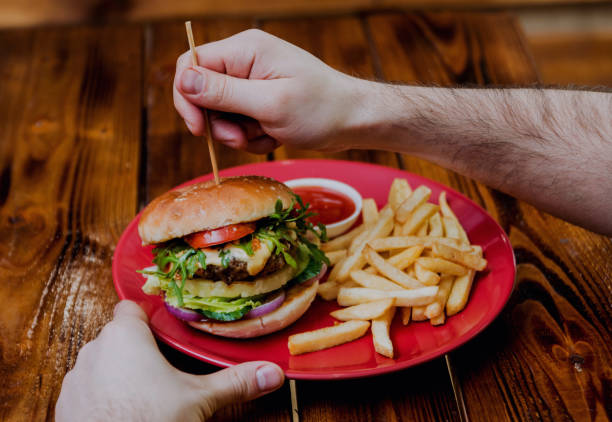 istock Young man eating a cheeseburger. 909321204