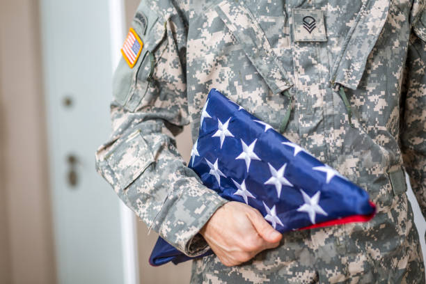 istock Soldier Presenting USA Flag Folded 909321254