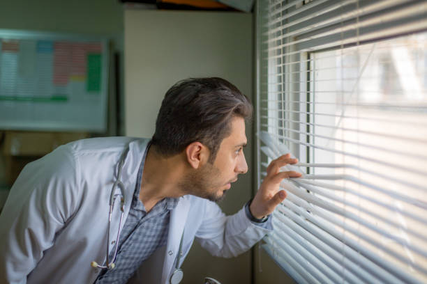 istock Confident doctor looking thru the window 909321306