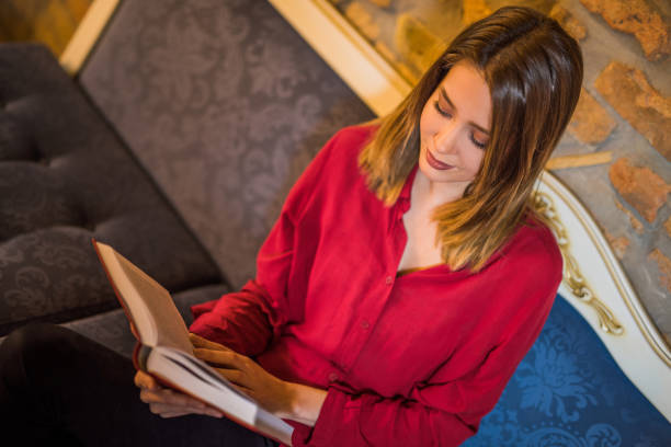 istock Beautiful young woman in red reading a book. 909325502
