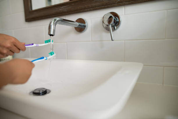 Bathroom sink with toothbrushes and running water. High quality photo.