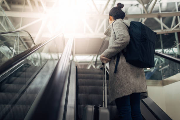 Young woman at the airport, on the escalator Young woman at the airport, on the escalator hand luggage stock pictures, royalty-free photos & images