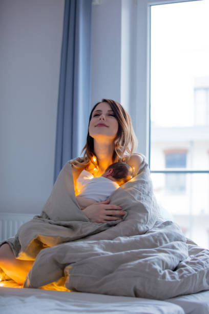 istock Mother and infant wrapped in blanket on bed. 909329284