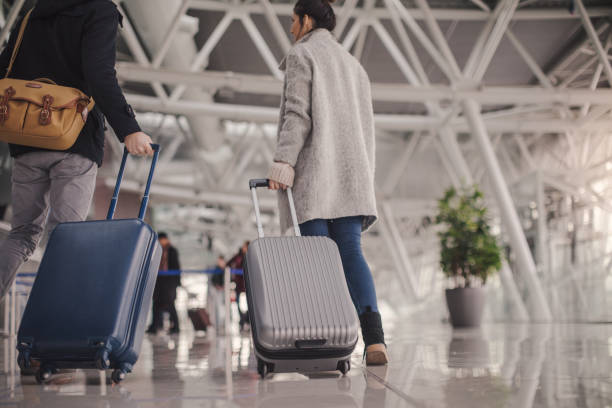 joven pareja llegando al aeropuerto de - equipaje de mano fotografías e imágenes de stock