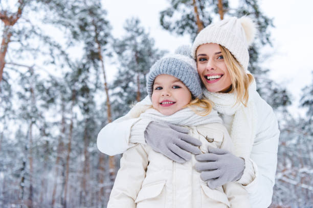 istock mother hugging daughter while standing in winter park 909335238