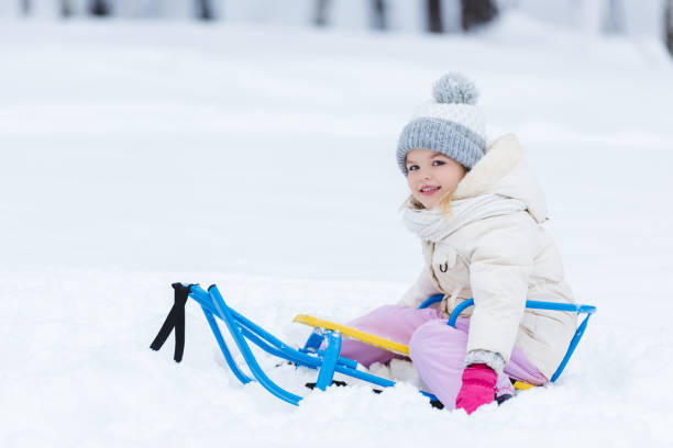 istock selective focus of smiling kid sitting on sledge in park 909335260