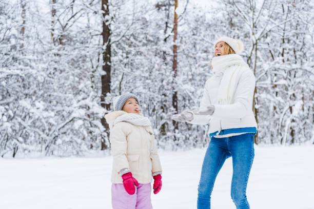 istock mother and daughter looking up while playing together in winter park 909340102
