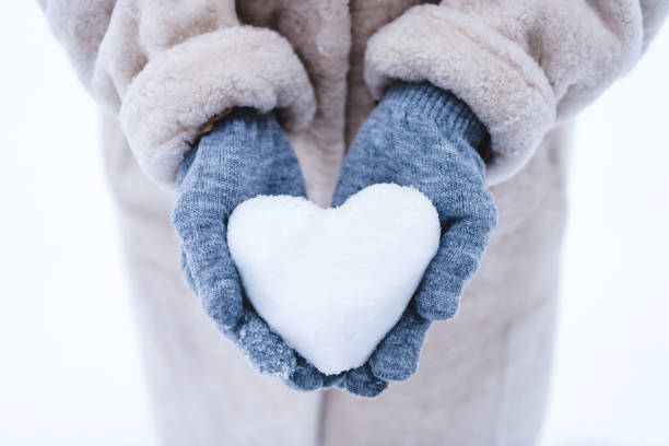 istock person holding heart symbol made from snow 909342936