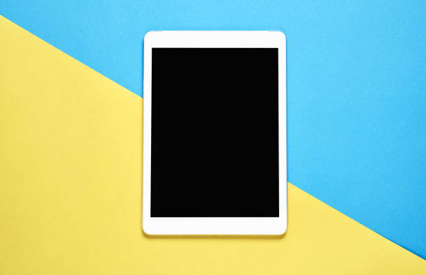 istock Top view, Modern workplace with tablet placed on a pastel yellow background. Copy space suitable for use in graphics. 909348894