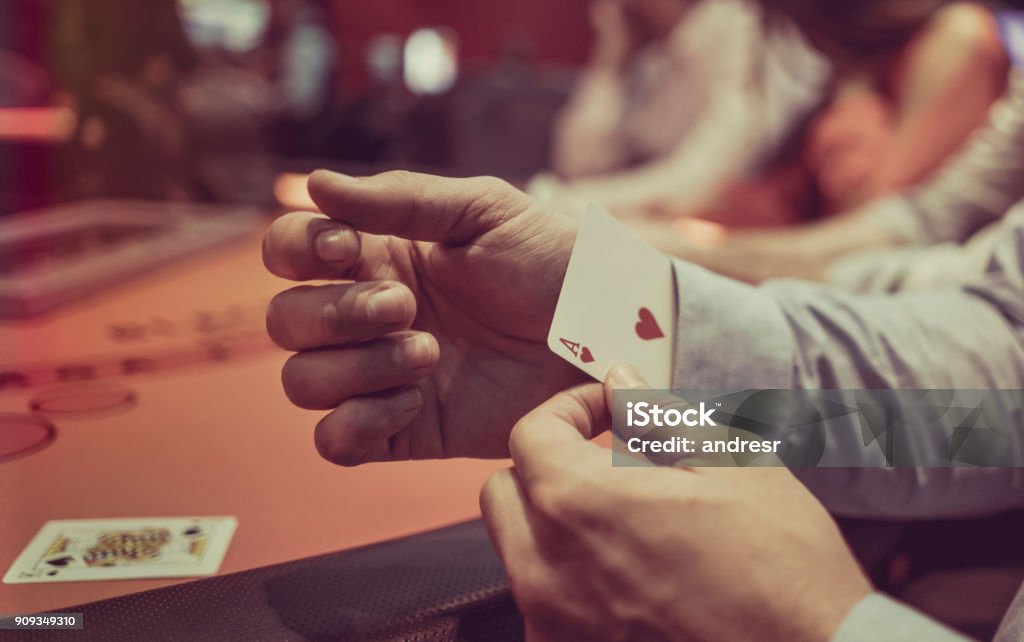 Man hiding an ace under in his sleeve at the casino Close-up on a man hiding an ace under in his sleeve while playing poker at the casino Dishonesty Stock Photo