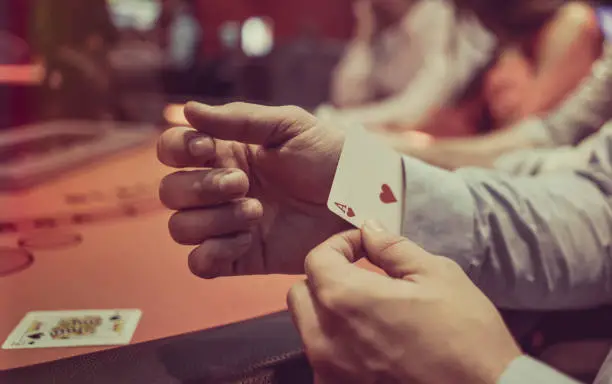 Close-up on a man hiding an ace under in his sleeve while playing poker at the casino