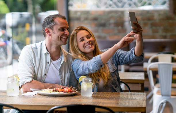 istock Happy couple taking a selfie at a restaurant 909349436