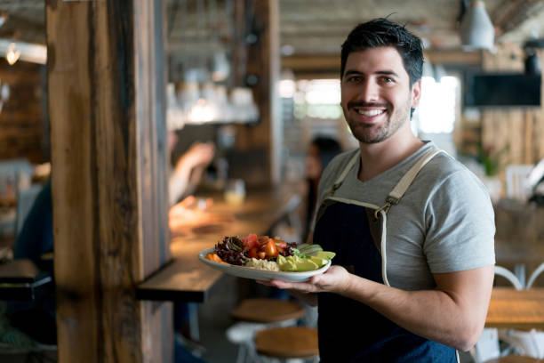 istock Happy waiter serving food at a restaurant 909349494