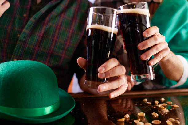 Close-up of unrecognizable men toasting with beer glass enjoying traditional festival at pub