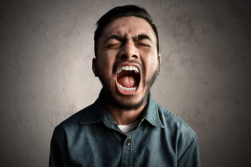 young man screaming angry portrait silhouette in studio on white background