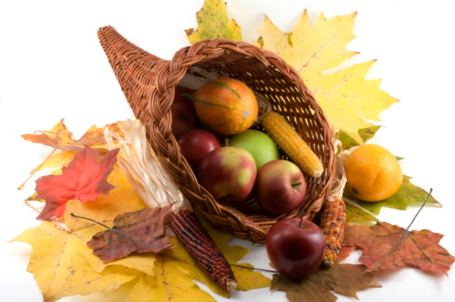Pumpkins, apples, cones, leaves, acorns, chestnuts, with fork and knife on a jute material for Thanksgiving dinner or Halloween.