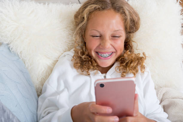 istock Tween, Preteen, Mixed Race Girl with braces laughs while using her smart phone 909367492