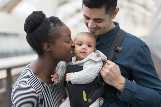 Photo of Adoring parents with their baby in a shopping mall