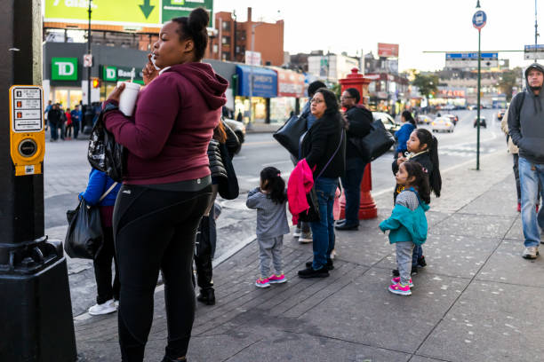 famiglia di persone in attesa di attraversare la strada nel centro di fordham heights, new york city, new york la sera - west bank foto e immagini stock