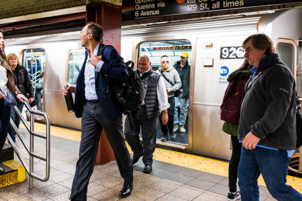New York City: People in underground platform transit in NYC Subway Station after work on commute with train, business people walking out arriving at rush hour