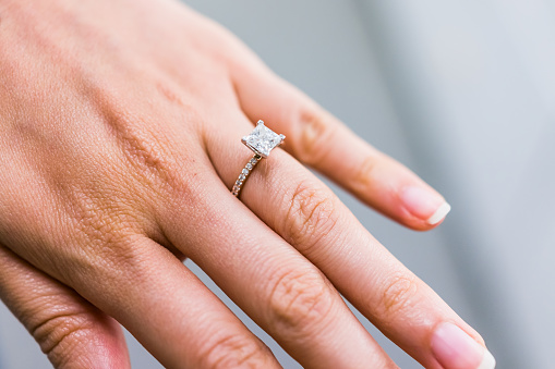Primer plano macro de princesa corte diamante anillo de compromiso en mano femenina de la mujer que muestra el detalle y la textura photo