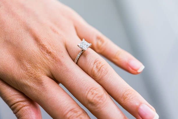 macro closeup of princess cut diamond engagement ring on woman's female hand showing detail and texture - engagement ring imagens e fotografias de stock