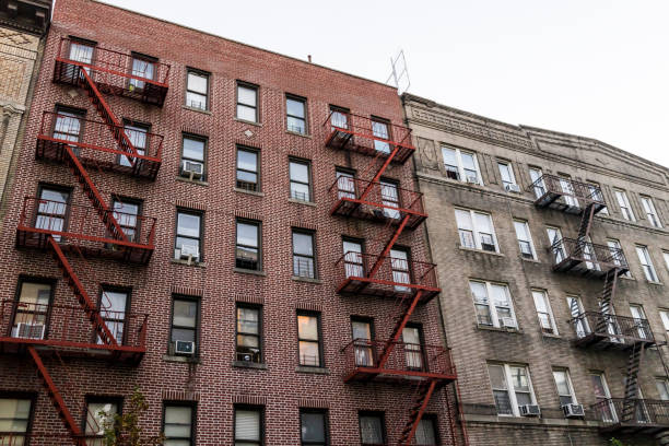 condominio de apartamentos de ladrillo edificio arquitectura exterior en alturas de fordham center, nyc, bronx, manhattan, nueva york con escapes de incendio, ventanas, unidades de aire acondicionado en la noche - poor area fotografías e imágenes de stock