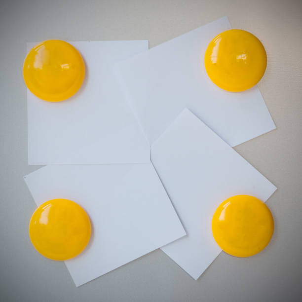Yellow magnet paper clip on gray refrigerator background for input text.