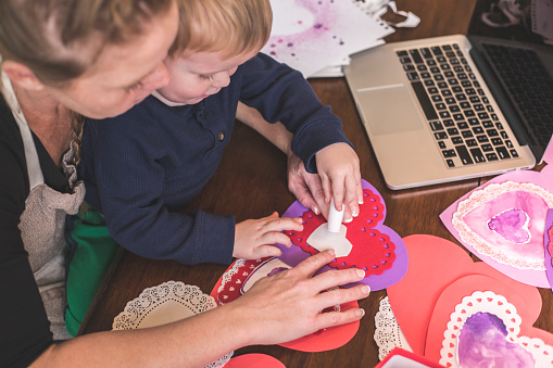 A stock photo of a mother making Valentines day crafts with her son.