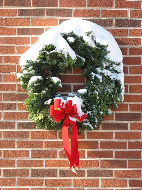 Śnieg objęte Evergreen Boże Narodzenie wieniec z czerwoną wstążką na Mur z cegły – zdjęcie