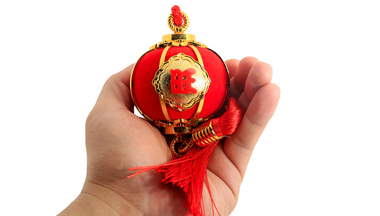 Hand holding a red spherical shape lantern for Chinese New year decoration isolated on white.  The Chinese word means fortune.
