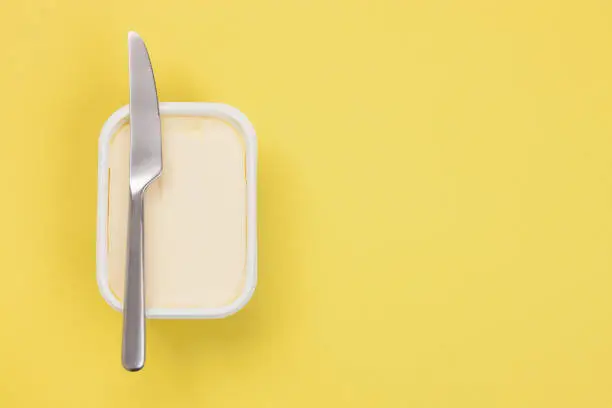 Butter and knife on yellow background