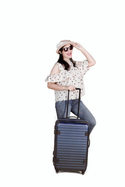 istock Beautiful woman standing with luggage on studio 909399652