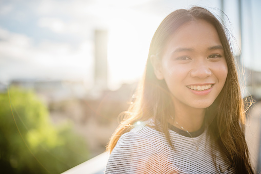 Young attractive millennial generation asian woman standing on the Pyrmont Bridge in Darling Harbour looking over with a bright smile. Darling Harbour. Downtown Sydney, New South Wales, Australia