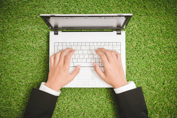 istock close up hand businessman working  on laptop on green grass 909404666