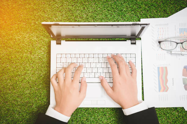 istock close up hand businessman working  on laptop on green grass 909406904