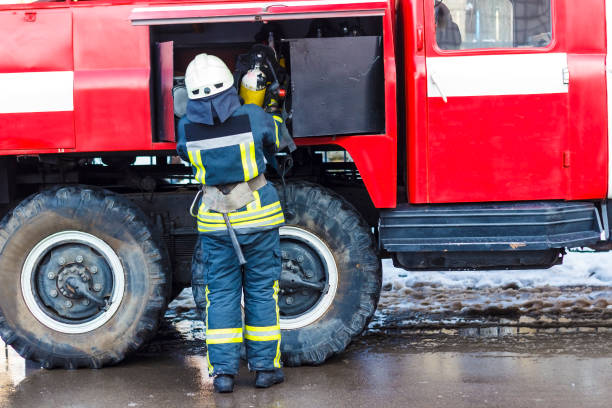 istock A fireman standing near a red fire engine and holding an oxygen balloon in his hands. 909407020