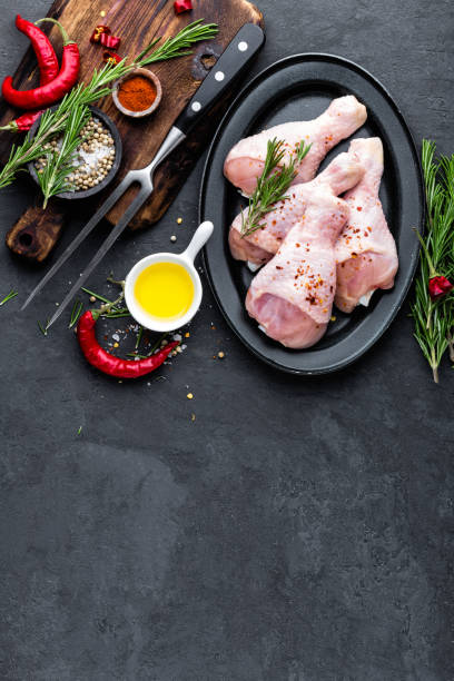 istock Chicken legs, drumsticks and ingredients for cooking, raw meat on black background, top view 909407714