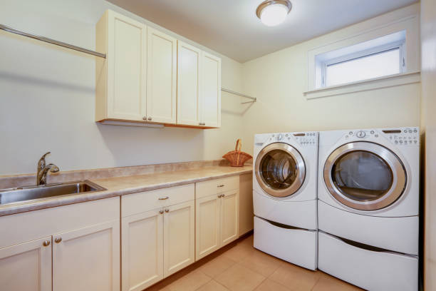 istock Light laundry room with creamy cabinets. 909408476