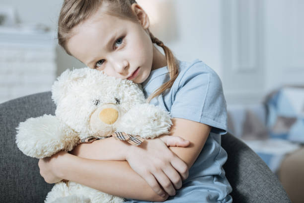 istock Lonely girl hugging her teddy bear 909411978