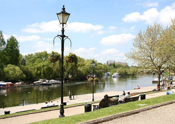 Serene River Scene with Boats and Lush Green Trees Under Cloudy Sky