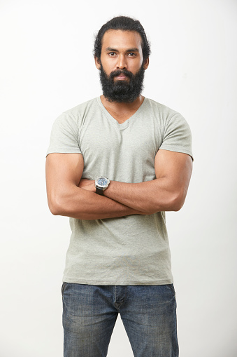 Bearded young man posing with crossed arms on white.